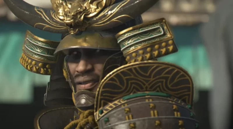 Imagem de Yasuke, um personagem samurai negro no jogo Assassin's Creed Shadows, usando uma armadura tradicional japonesa com detalhes dourados.